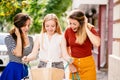 Three women look into shopping bags near mall