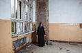Young goth woman stands in the room of an abandoned house