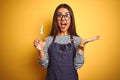 Young beautiful hairdresser woman holding scissors standing over isolated yellow background very happy and excited, winner Royalty Free Stock Photo