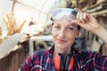 Young beautiful handy professional happy female strong carpenter portrait wearing protective goggles working in Royalty Free Stock Photo