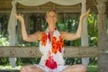 Young beautiful and happy American tourist woman practicing yoga and meditation sitting in lotus position at outdoors hut enjoying Royalty Free Stock Photo