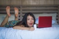 Young beautiful happy Asian American girl using credit card internet banking on laptop computer at home in bed shopping online e-c Royalty Free Stock Photo