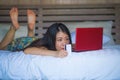 Young beautiful happy Asian American woman using credit card internet banking on laptop computer at home in bed shopping online e- Royalty Free Stock Photo