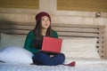 Young beautiful happy Asian Chinese girl in winter beamy relaxed on bed using laptop computer thoughtful and pensive enjoying soci Royalty Free Stock Photo