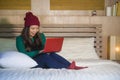 Young beautiful and happy Asian Chinese girl in winter beamy sitting relaxed on bed using laptop computer having fun enjoying onli Royalty Free Stock Photo