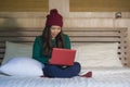 Young beautiful and happy Asian Chinese girl in winter beamy sitting relaxed on bed using laptop computer having fun enjoying onli Royalty Free Stock Photo