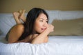 Young beautiful and happy Asian Chinese Korean lying on bed in the morning at home bedroom or hotel room feeling cheerful and rela Royalty Free Stock Photo