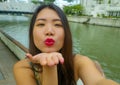 Young beautiful and happy Asian Chinese tourist woman taking selfie photo with mobile phone smiling cheerful having fun sending ki Royalty Free Stock Photo