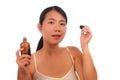 Young beautiful and happy Asian Chinese woman applying skincare wrinkle prevention serum treatment or aging beauty product on her