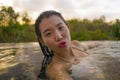 Young beautiful and happy Asian Chinese woman in bikini enjoying sunset taking selfie at amazing jungle resort infinity pool Royalty Free Stock Photo