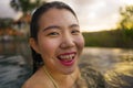 Young beautiful and happy Asian Chinese woman in bikini enjoying sunset taking selfie at amazing jungle resort infinity pool Royalty Free Stock Photo