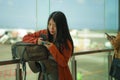 Young beautiful and happy Asian Chinese woman checking mobile phone holding passport at airport departure lounge carrying backpack Royalty Free Stock Photo