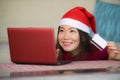 Young beautiful and happy Asian Chinese woman in Christmas Santa Claus hat holding credit card using laptop computer for internet Royalty Free Stock Photo