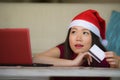 Young beautiful and happy Asian Chinese woman in Christmas Santa Claus hat holding credit card using laptop computer for internet Royalty Free Stock Photo