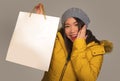 Young beautiful and happy Asian Chinese woman in cool winter hat holding shopping bag excited buying Christmas present smiling Royalty Free Stock Photo