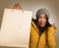 Young beautiful and happy Asian Chinese woman in cool winter hat holding shopping bag excited buying Christmas present smiling Royalty Free Stock Photo