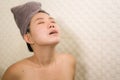 Young beautiful and happy Asian Chinese woman with head wrapped in towel smiling fresh and cheerful after taking shower enjoying Royalty Free Stock Photo