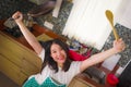 Young beautiful and happy Asian Chinese woman in kitchen apron holding pan and spoon smiling cheerful enjoying domestic chores Royalty Free Stock Photo