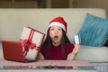 Young beautiful and happy Asian Chinese woman in Santa hat holding credit card and Christmas present box using laptop computer for Royalty Free Stock Photo