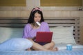 Young beautiful happy Asian Chinese woman using credit card internet banking on laptop computer at home in bed smiling shopping on Royalty Free Stock Photo