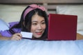 Young beautiful happy Asian Chinese woman using credit card internet banking on laptop computer at home in bed smiling shopping on Royalty Free Stock Photo