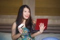 Young beautiful happy Asian Chinese woman using credit card internet banking on laptop computer at home in bed smiling shopping on Royalty Free Stock Photo