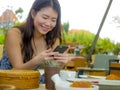 Young beautiful and happy Asian Chinese woman using internet social media app on mobile phone smiling cheerful enjoying breakfast Royalty Free Stock Photo