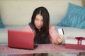 Young beautiful and happy Asian Chinese woman in winter sweater holding credit card and Christmas present box using laptop for int Royalty Free Stock Photo