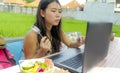 Young beautiful and happy Asian Chinese woman working outdoors with laptop computer networking green grass background cafe as digi Royalty Free Stock Photo