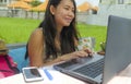 Young beautiful and happy Asian Chinese woman working outdoors with laptop computer networking green grass background cafe as digi Royalty Free Stock Photo