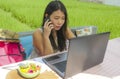 Young beautiful and happy Asian Chinese woman working outdoors with laptop computer networking green grass background cafe as digi Royalty Free Stock Photo