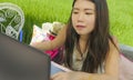 Young beautiful and happy Asian Chinese woman working outdoors with laptop computer networking green grass background cafe as digi Royalty Free Stock Photo