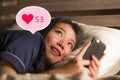 Young beautiful and happy Asian girl getting social media likes. Gorgeous Korean woman in bed at night excited getting positive