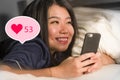 Young beautiful and happy Asian girl getting social media likes. Gorgeous Korean woman in bed at night excited getting positive