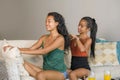 Young beautiful happy Asian girlfriends at home couch with one girl brushing the hair of the other woman helping preparing for dat