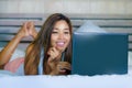 Young beautiful and happy Asian Hispanic mixed race woman smiling at home bedroom lying on bed using internet on computer laptop r Royalty Free Stock Photo