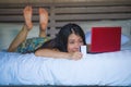 Young beautiful happy Asian Japanese girl using credit card internet banking on laptop computer at home in bed shopping online e-c Royalty Free Stock Photo