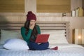 Young beautiful happy Asian Japanese girl in winter beamy sitting relaxed on bed using laptop computer having fun enjoying online Royalty Free Stock Photo