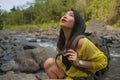 Young beautiful and happy Asian Japanese woman carrying backpack trekking on mountains crossing river enjoying holiday nature and Royalty Free Stock Photo