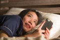 Young beautiful and happy Asian Japanese woman in pajamas using mobile phone social media texting with her boyfriend or enjoying Royalty Free Stock Photo