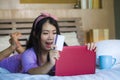 Young beautiful happy Asian Japanese woman using credit card internet banking on laptop computer at home in bed smiling shopping o Royalty Free Stock Photo