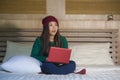 Young beautiful happy Asian Korean girl in winter beamy sitting relaxed on bed using laptop computer having fun enjoying online mo Royalty Free Stock Photo