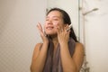 Young beautiful and happy Asian Korean woman applying serum facial skin care and face treatment in the bathroom enjoying morning