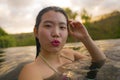 Young beautiful and happy Asian Korean woman in bikini enjoying sunset taking selfie at amazing jungle resort infinity pool Royalty Free Stock Photo