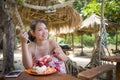 Young beautiful and happy Asian Korean woman in bikini having lunch brunch or breakfast at tropical paradise beach resort Royalty Free Stock Photo