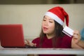 Young beautiful and happy Asian Korean woman in Christmas Santa Claus hat holding credit card using laptop computer for internet o Royalty Free Stock Photo