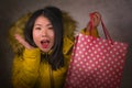 Young beautiful and happy Asian Korean woman in cool winter jacket holding shopping bag excited buying Christmas present smiling