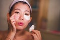 Young beautiful and happy Asian Korean woman smiling to bathroom mirror applying hydrating eye patches under the eyes in beauty Royalty Free Stock Photo