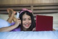 Young beautiful happy Asian Korean woman using credit card internet banking on laptop computer at home in bed smiling shopping onl Royalty Free Stock Photo