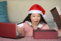Young beautiful and happy Asian Korean woman wearing Santa hat holding credit card and Christmas present box using laptop computer Royalty Free Stock Photo